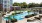 Spacious poolside view with lots of palm trees and reclining charis